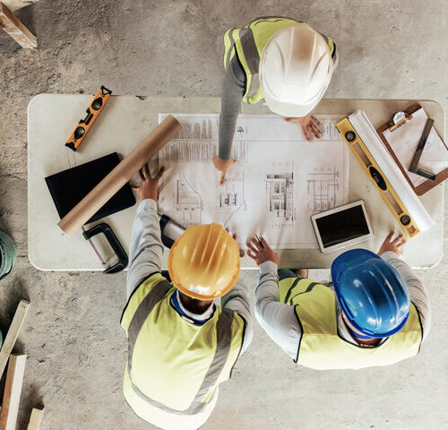 Construction professionals collaborating with digital tablets on a job site, illustrating the human and technological challenges of BIM2Field integration.