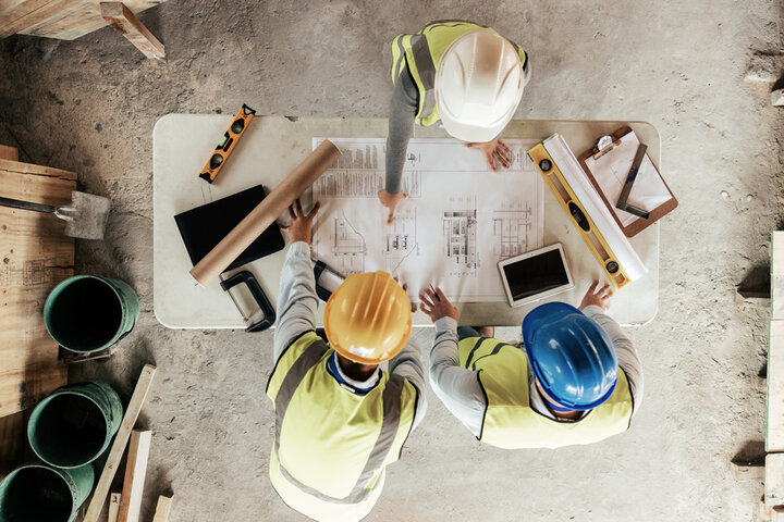 Construction professionals collaborating with digital tablets on a job site, illustrating the human and technological challenges of BIM2Field integration.